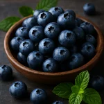 Fresh blueberries in a rustic wooden bowl with mint leaves on a dark wooden background — a natural superfood packed with antioxidants."